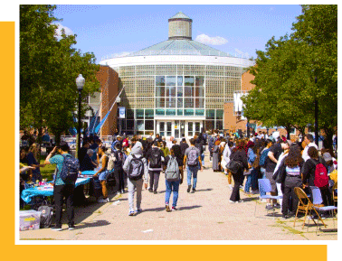 students in a large sidewalk in front of a glass front building